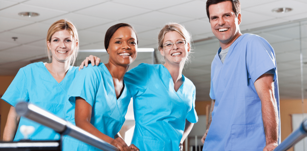 A group of travel therapists wearing scrubs, smiling together.