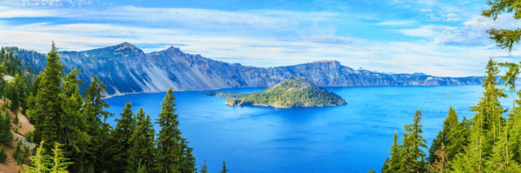 A breathtaking view of the pristine Crater Lake National Park, nestled within the volcanic caldera in Oregon. The deep blue waters and stunning surroundings offer an awe-inspiring camping experience for visitors seeking the magic of this natural wonder.