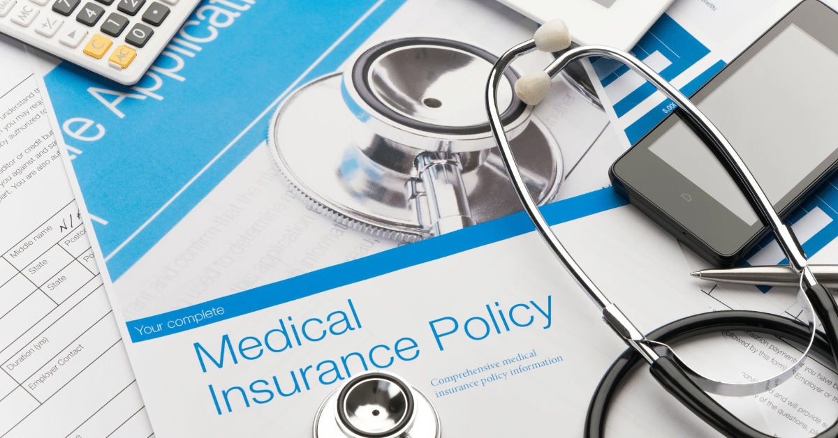 Travel Nurse Health Insurance Options | An image of a health insurance policy brochure placed on a desk, surrounded by essential items such as a stethoscope, calculator, and cellphone. This imagery emphasizes the significance of health coverage choices for travel nurses, highlighting the practical tools and resources they need to make informed decisions about their well-being while on the move.