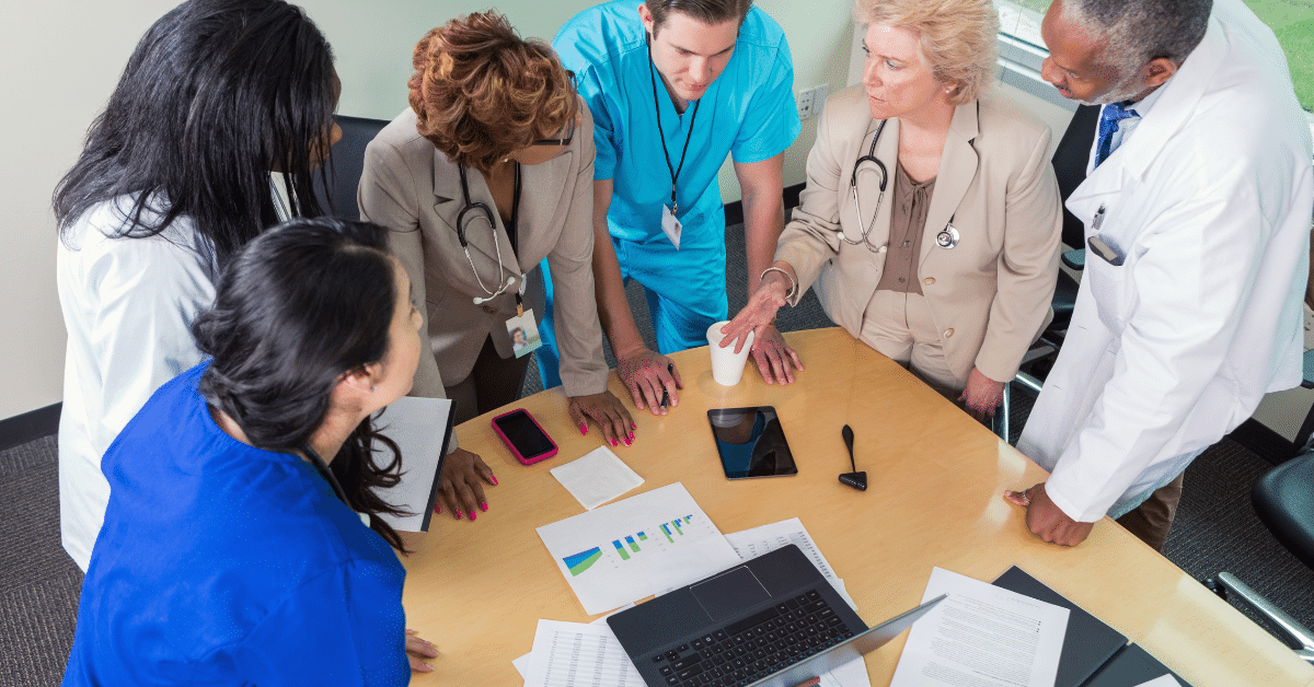 A team of hospital doctors, nurses, and administrators engaged in a meeting, exemplifying the collaborative and dynamic nature of a day in the life of a travel nurse.