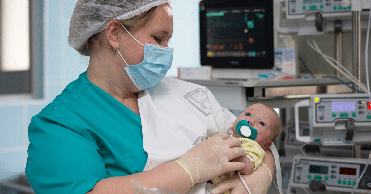 An experienced neonatal nurse gently cradles a fragile baby in the neonatal intensive care unit (NICU). The nurse wears protective gloves and is focused on providing attentive care to the tiny patient, who is surrounded by medical equipment and monitors. The soft, dimly lit environment of the NICU ensures a peaceful and nurturing atmosphere for the newborn's early days.