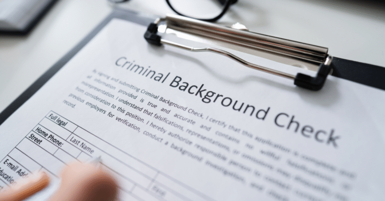 Close-up of a travel nurse's hand meticulously filling out a criminal background check form, highlighting the importance of thorough screenings in the profession.