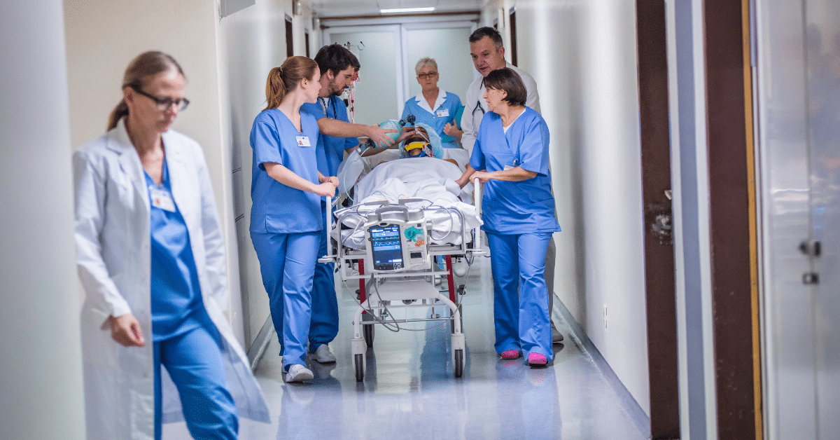 Emergency room nurses in a bustling medical environment carefully transport an injured patient on a hospital gurney.