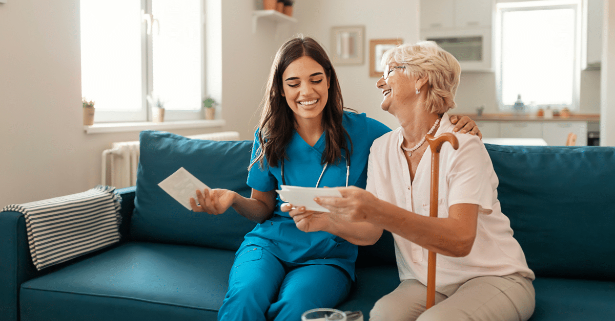 Senior woman joyfully shares photos with a compassionate nurse in a skilled nursing facility, fostering a warm connection through laughter and cherished memories. Illustrating the one of the benefits of working in a Skilled Nursing Facility.