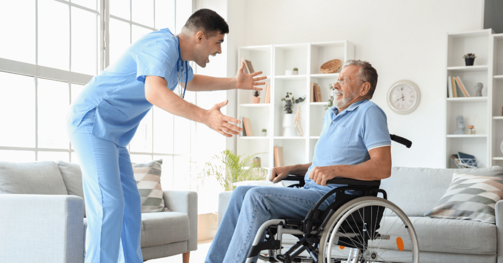 A male nurse standing over a patient in a wheelchair, displaying anger and yelling, while the patient looks scared and confused. This image illustrates the negative impact of attitudes on patient care and highlights the importance of understanding how nurses' attitudes can affect patient care.