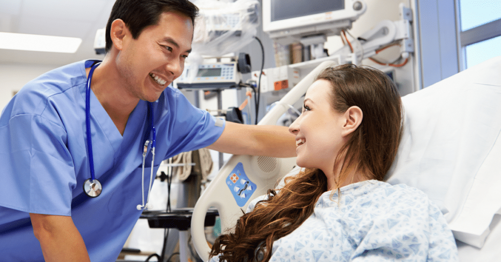 An image of a male nurse with a warm, smiling expression leaning over a patient during a conversation. The patient looks happy and comforted, reflecting positive attitudes in healthcare. This image illustrates how nurses' attitudes can have a significant impact on patient care.