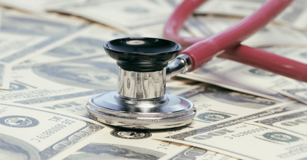 A stethoscope rests on top of a stack of various denominations of banknotes, symbolizing December pay rates for travel nursing.